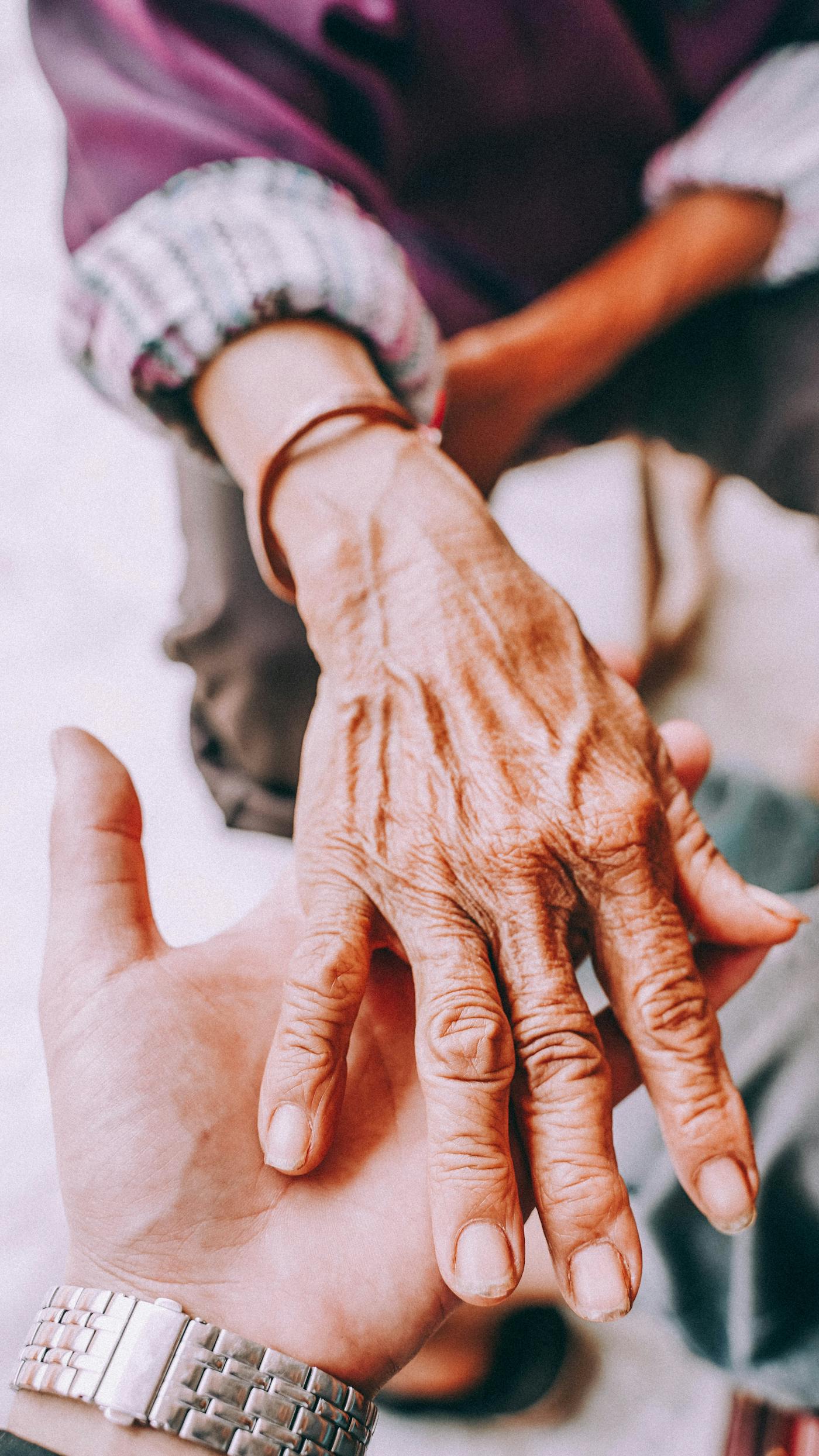 Young hand tenderly holding an elderly hand