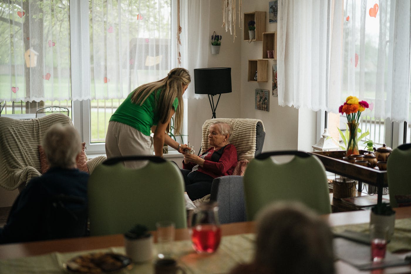Carer gently serving an elderly woman in a comfortable living space