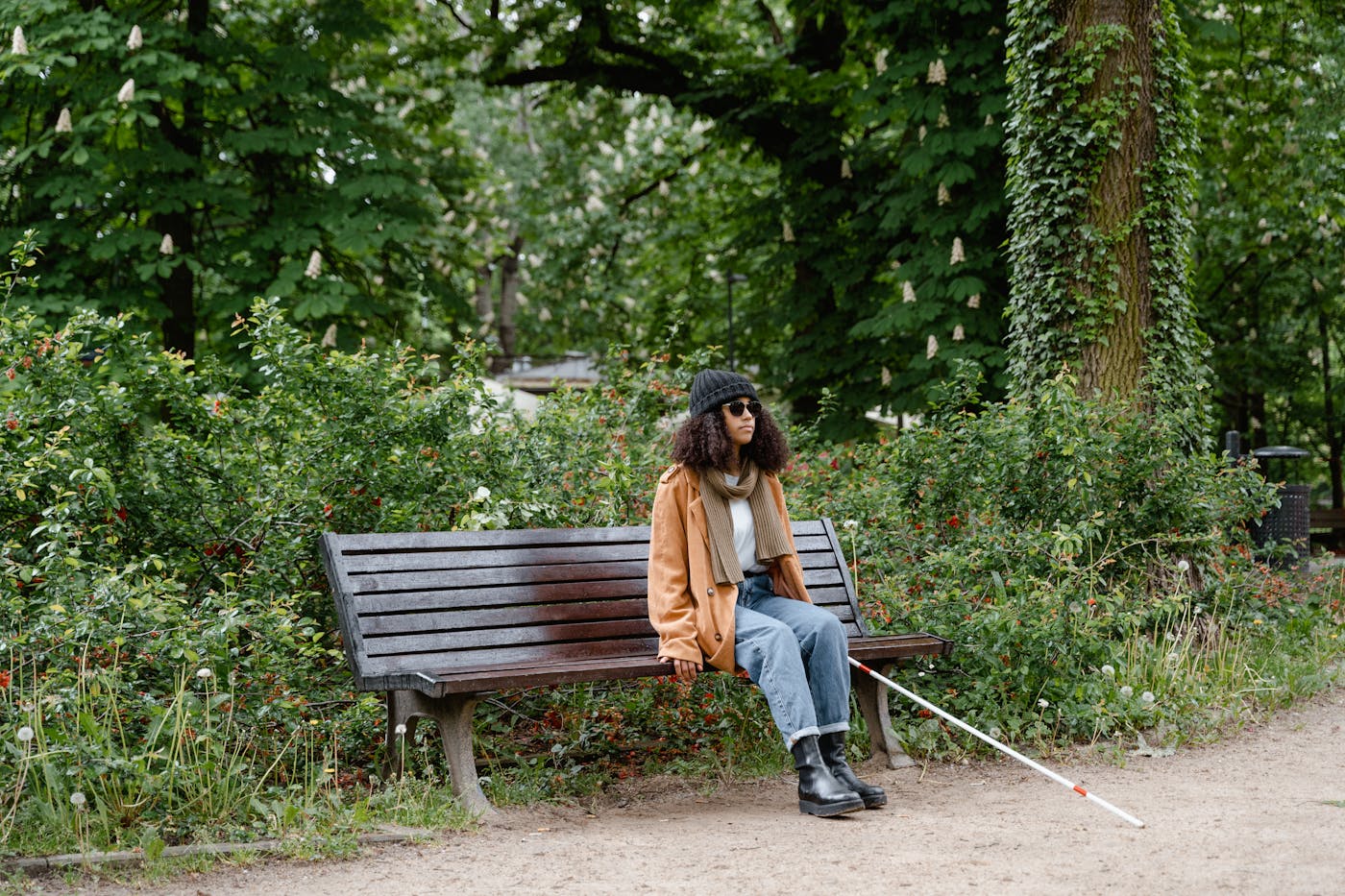 Woman with a white cane seated in a peaceful park